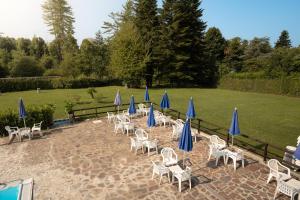 grupa krzeseł i niebieskich parasoli na patio w obiekcie Terme Di Monte Valenza w mieście Valenza