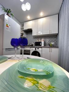 Una cocina con dos vasos azules y un plato sobre una mesa. en Квартира на Тимирязева 58 Luxury Central, en Almaty 5 fotos más
