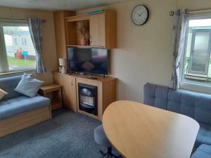 a living room with a tv and a couch and a table at Escape to the bay- arnside escapes in Morecambe +6 photos