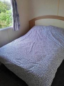 a bedroom with a bed with a blue comforter and a window at Escape to the bay- arnside escapes in Morecambe