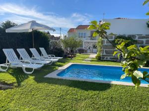 a group of chairs and an umbrella next to a pool at Casa do Albano in Viana do Castelo