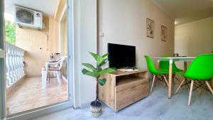 a living room with a television and a table with green chairs at Bratanov Sveti Vlas Apartments in Sveti Vlas
