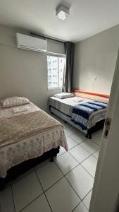 um quarto com duas camas e uma janela em lindo apartamento de frente para à praia de pajuçara em Maceió