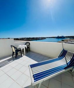 a blue and white bench on a balcony with a table at Hotel Giglio in Lampedusa