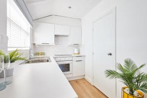 a white kitchen with white cabinets and a sink at Host & Stay - Sunnyside Studio in Bempton +6 photos