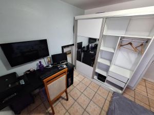 Habitación con escritorio, ordenador y armario. en Quarto em Apto confortável 10 min da praia do Recreio RJ, en Río de Janeiro