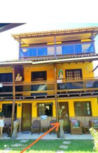 un grande edificio giallo con una freccia arancione sopra di Triplex 3 Suítes 10 PESSOAS Cond Aldeia dos Pescadores Praia do Forte a Praia do Forte