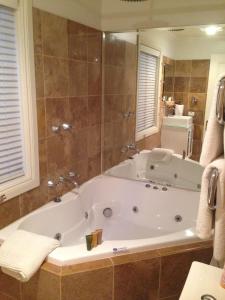 a large bath tub in a bathroom with a mirror at Aldgate Creek Cottage Bed and Breakfast in Aldgate