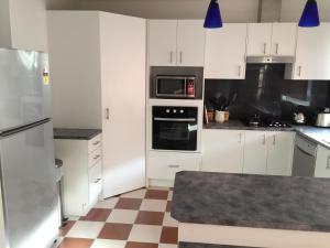 a kitchen with white cabinets and a checkered floor at Serenity in Narre Warren North