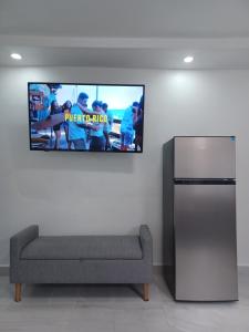 a living room with a couch and a tv on the wall at Black & White Comfort Studio in San Juan