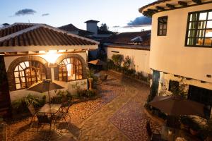 an outdoor patio with tables and umbrellas in front of a building at Hotel Beth Sarim in Villa de Leyva