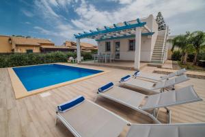 a swimming pool with lounge chairs next to a house at Villa Capri in Campofelice di Roccella