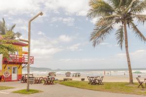 a beach with tables and chairs and a palm tree at Com garagem e banheira a 150m da praia N1188 in Itapema
