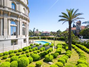 a garden with a palm tree and a building at Sofitel Montevideo Casino Carrasco & Spa in Montevideo