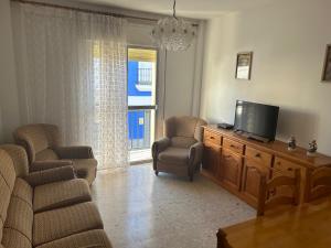 a living room with a flat screen tv and chairs at Pisos Isla Cristina 1 in Isla Cristina