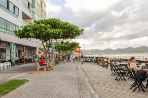 a boardwalk near the beach with people sitting on benches at Apto em condomínio Pé na Areia em Itapema N1672 in Itapema