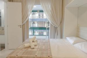 a teddy bear laying on a bed in a bedroom at Apto em condomínio Pé na Areia em Itapema N1672 in Itapema