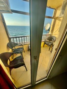 a balcony with chairs and a view of the ocean at ALEX HOMES - Sporting Cozy Apartments with Direct Sea View in Alexandria +43 photos