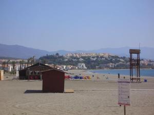 a beach with a building and people on the beach at Spacious duplex apartment families and couples in Manilva