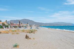 a beach with people sitting on the sand and the ocean at Spacious duplex apartment families and couples in Manilva