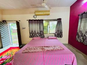 a bedroom with a large bed with pink walls and windows at Royal villa resort in Amravati