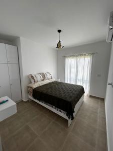 Un dormitorio con una cama y una ventana grande en Chalet in Mountain View ras elhekma, en Ras Elhekma