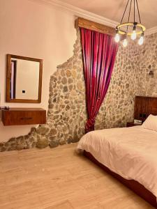 a bedroom with a stone wall with a bed and a mirror at KAZA Aouchtame 1 in Tétouan