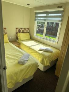two beds in a room with a window at Lodge Retreat 8 - Haggerston Castle in Berwick-Upon-Tweed +6 photos