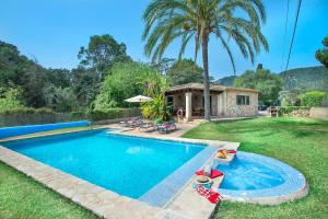 a swimming pool with a palm tree and a house at Can Pep by Vintage Travel in Pollença