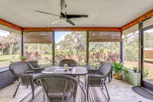 a screened porch with a table and chairs and a ceiling fan at Lovely Retreat Walk to Manasota Key Beach! in Englewood