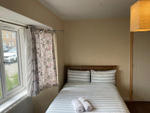 a bed with two towels on it next to a window at Rainbow in London +5 photos