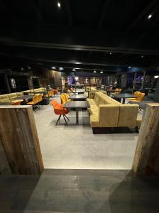 a room with couches and tables and yellow chairs at Alpotel Dolomiten in Molveno