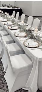 a long table with white tables and white chairs at Plantation Inn in Houma