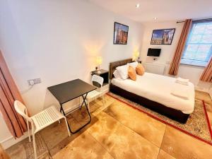 a bedroom with a bed and a table and a desk at The City Pad in Gloucester
