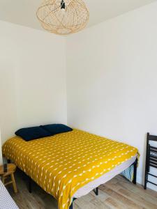 un lit dans une chambre avec une couverture jaune dans l'établissement Chambres rénovées proches de Paris Centre, des sites olympiques, avec belle terrasse calme, à Argenteuil