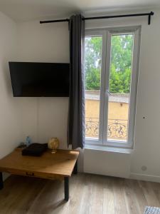Cette chambre dispose d'une grande fenêtre et d'une table en bois. dans l'établissement Chambres rénovées proches de Paris Centre, des sites olympiques, avec belle terrasse calme, à Argenteuil