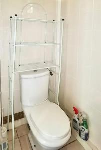 a bathroom with a toilet with shelves on the wall at Bungalow charmant au Gosier in Le Gosier