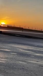 eine Autobahn mit Windmühlen im Hintergrund bei Sonnenuntergang in der Unterkunft Casa de Praia in Luis Correia