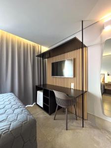a bedroom with a desk with a television and a bed at Hotel Merion in Pato Branco