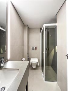 a bathroom with a toilet and a glass shower at Hotel Merion in Pato Branco +28 photos