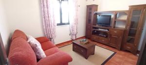a living room with a red couch and a tv at EnSan CIPRIAN Casa Lula in Cervo