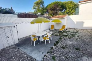 a patio with a table and chairs with yellow umbrellas at Casa Patrón in Costa da Caparica