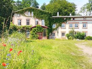 an old house with a field of grass and flowers at Alt Krassow Lakeside Retreat in Krassow