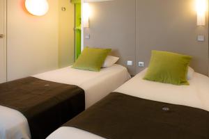 two beds with green pillows in a room at Hotel inn Design Laval in Laval