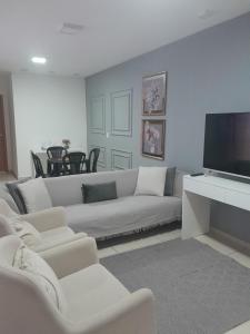 a living room with a white couch and a flat screen tv at Casa ampla com garagem e Wi-Fi Lagoa Seca, Juazeiro do norte -CE in Juazeiro do Norte