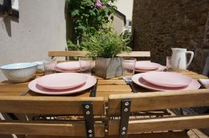 a wooden table with pink plates and glasses on it at Ma petite maison bretonne in Guimiliau