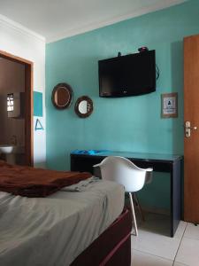 マリンガにあるKit Net 5 azul cama casalのベッドルーム1室(ベッド1台、デスク、壁掛けテレビ付)