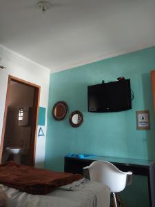 マリンガにあるKit Net 5 azul cama casalの青い壁にテレビが備わるベッドルーム1室 +13枚の写真