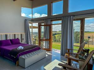 a bedroom with a purple bed and a large window at Cabana com jacuzzi e churrasqueira - Ibiuna SP in Bairro Murundu