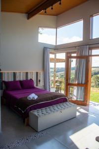 a bedroom with a purple bed and a large window at Cabana com jacuzzi e churrasqueira - Ibiuna SP in Lajeado do Salto